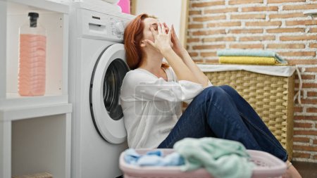 Téléchargez les photos : Jeune rousse femme laver les vêtements stressé à la buanderie - en image libre de droit