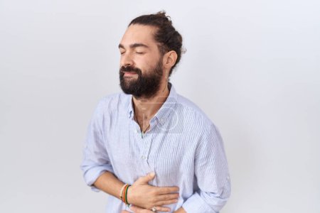 Photo for Hispanic man with beard wearing casual shirt with hand on stomach because indigestion, painful illness feeling unwell. ache concept. - Royalty Free Image