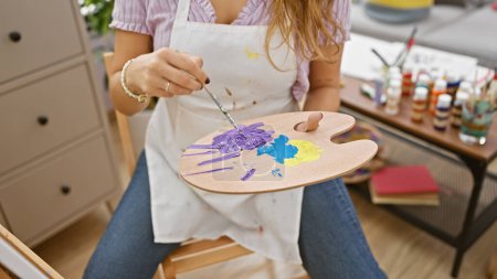 Téléchargez les photos : Femme artiste talentueuse mélangeant passionnément les couleurs sur sa palette, les mains au travail dans un atelier d'art dynamique - en image libre de droit