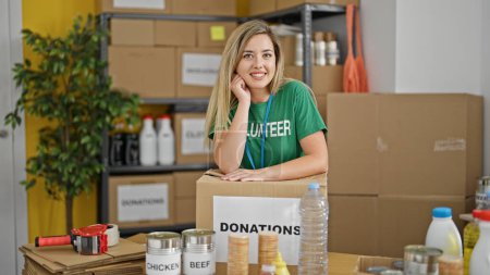 Téléchargez les photos : Jeune femme blonde bénévole souriant confiance debout au centre de charité - en image libre de droit