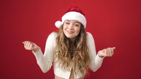 Photo for Young beautiful hispanic woman wearing christmas hat doing i dont know gesture at street - Royalty Free Image