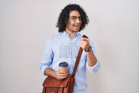 Téléchargez les photos : Homme hispanique avec les cheveux bouclés boire une tasse de café emporter les doigts pointant vers la caméra avec un visage heureux et drôle. bonne énergie et vibes. - en image libre de droit