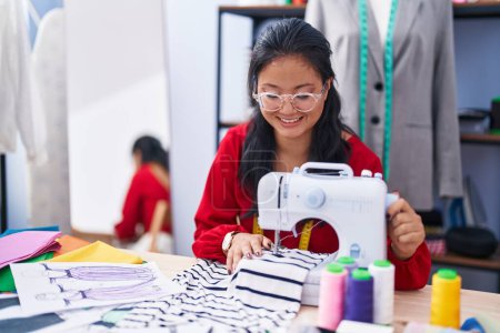 Téléchargez les photos : Young chinese woman tailor smiling confident using sewing machine at atelier - en image libre de droit