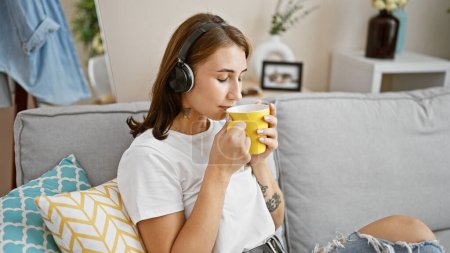 Téléchargez les photos : Young woman listening to music drinking coffee at home - en image libre de droit