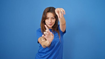 Téléchargez les photos : Jeune belle femme hispanique souriant danse confiante sur fond bleu isolé - en image libre de droit