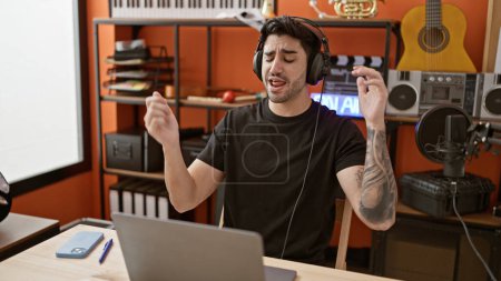 Photo for Young hispanic man musician listening to music dancing at music studio - Royalty Free Image