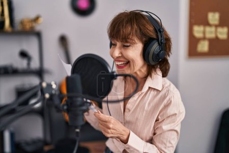 Téléchargez les photos : Femme musicienne d'âge moyen souriant chanson de chant confiante au studio de musique - en image libre de droit