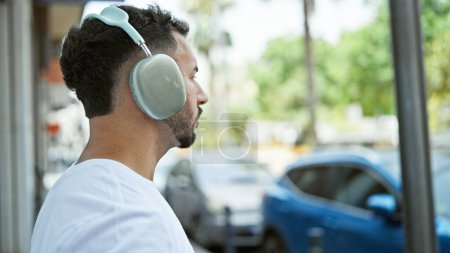 Téléchargez les photos : Jeune homme arabe écoutant de la musique dans la rue - en image libre de droit