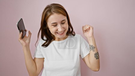 Téléchargez les photos : Jeune femme dansant en écoutant de la musique sur smartphone sur fond rose isolé - en image libre de droit