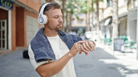 Téléchargez les photos : Jeune homme portant des vêtements de sport écoutant de la musique regardant la rue - en image libre de droit