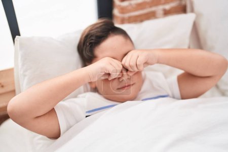 Téléchargez les photos : Adorable garçon hispanique se réveiller en frottant les yeux dans la chambre - en image libre de droit