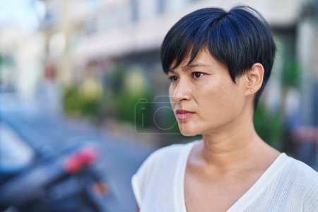 Photo for Middle age chinese woman looking to the side with serious expression at street - Royalty Free Image