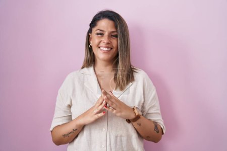 Photo for Blonde woman standing over pink background hands together and fingers crossed smiling relaxed and cheerful. success and optimistic - Royalty Free Image