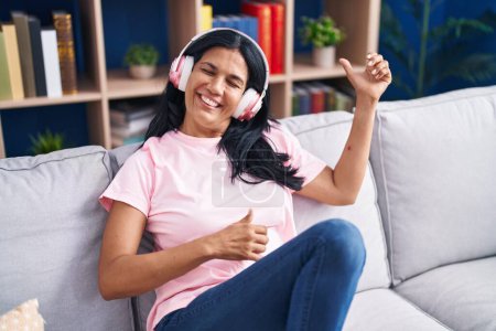 Photo for Middle age hispanic woman listening to music doing guitar gesture at home - Royalty Free Image