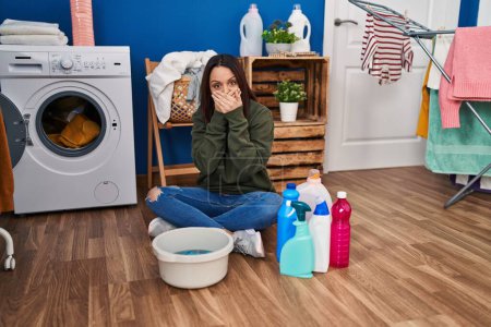 Photo for Young hispanic woman doing laundry washing by hand shocked covering mouth with hands for mistake. secret concept. - Royalty Free Image