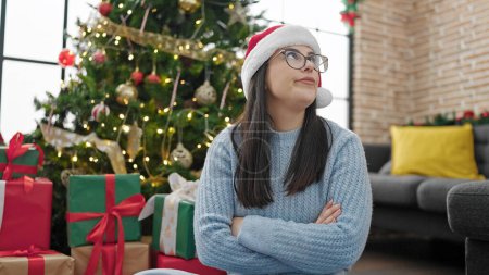 Photo for Young hispanic woman sitting upset wearing christmas hat at home - Royalty Free Image