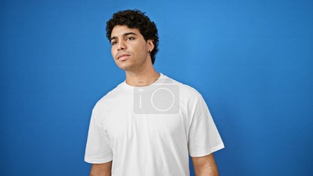Photo for Young latin man looking for someone over isolated blue background - Royalty Free Image