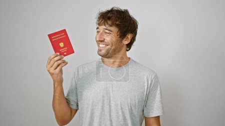Téléchargez les photos : Jeune homme joyeux, patriote rayonnant, tient avec confiance son passeport autrichien contre un mur blanc isolé, prêt pour l'aventure européenne! - en image libre de droit