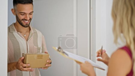 Photo for Young hispanic man receiving package signing on clipboard at street - Royalty Free Image