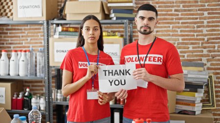 Photo for Man and woman volunteers standing together holding thank you paper at charity center - Royalty Free Image