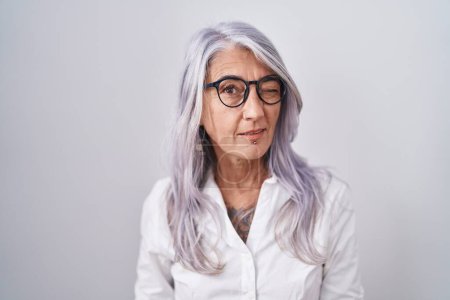 Photo for Middle age woman with tattoos wearing glasses standing over white background winking looking at the camera with sexy expression, cheerful and happy face. - Royalty Free Image