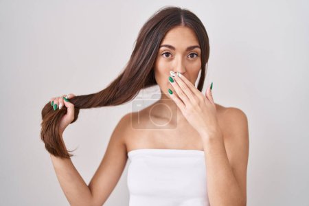 Photo for Young hispanic woman holding hair with hand covering mouth with hand, shocked and afraid for mistake. surprised expression - Royalty Free Image