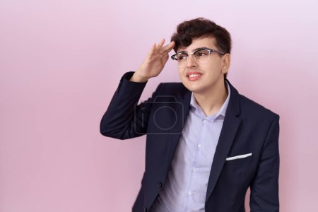 Photo for Young non binary man with beard wearing suit and tie very happy and smiling looking far away with hand over head. searching concept. - Royalty Free Image