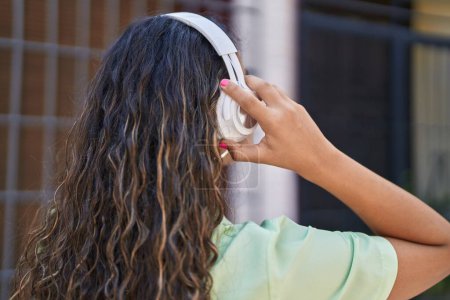 Foto de Joven mujer hispana hermosa escuchando música en la calle - Imagen libre de derechos