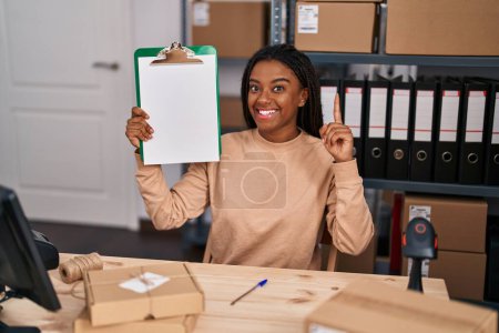 Photo for Young african american with braids working at small business ecommerce showing clipboard surprised with an idea or question pointing finger with happy face, number one - Royalty Free Image
