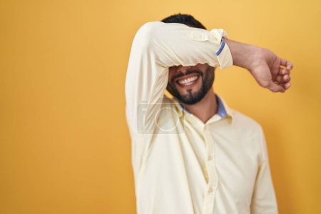 Photo for Hispanic young man wearing business clothes and glasses covering eyes with arm smiling cheerful and funny. blind concept. - Royalty Free Image