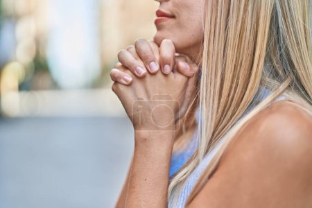 Photo for Young blonde woman praying at street - Royalty Free Image