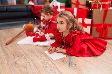 Photo for Adorable girls drawing on paper celebrating christmas at home - Royalty Free Image