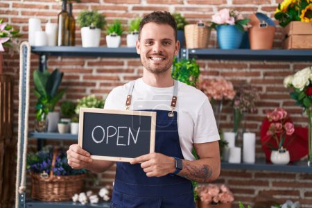 Photo for Young hispanic man working at florist holding open sign smiling with a happy and cool smile on face. showing teeth. - Royalty Free Image