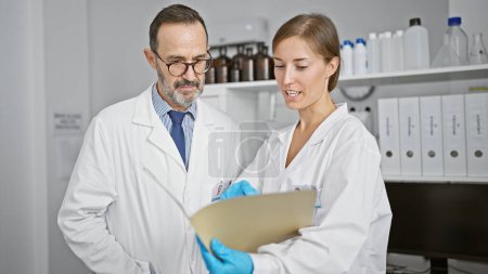 Foto de Dos científicos leyendo el documento juntos hablando en el laboratorio - Imagen libre de derechos