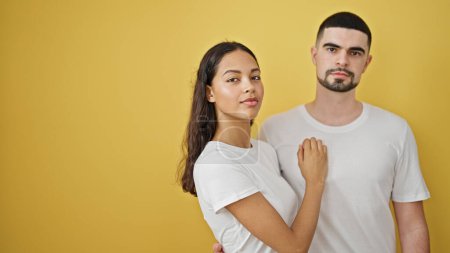 Photo for Beautiful couple sporting serious faces on an isolated yellow background, the face of modern love and relationships - Royalty Free Image