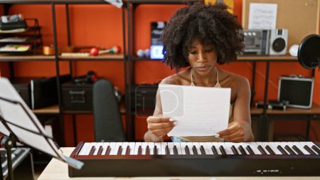 Foto de Músico afroamericano tocando piano leyendo hoja de música en estudio de música - Imagen libre de derechos