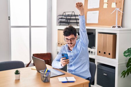 Téléchargez les photos : Young caucasian man business worker using smartphone with winner expression at office - en image libre de droit