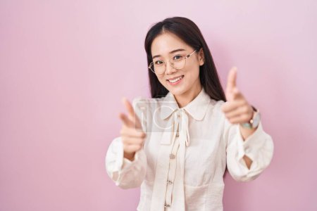 Photo for Young chinese woman standing over pink background pointing fingers to camera with happy and funny face. good energy and vibes. - Royalty Free Image