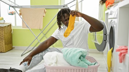 Téléchargez les photos : Afro-Américain homme lavage vêtements odeur sale chaussette à buanderie - en image libre de droit