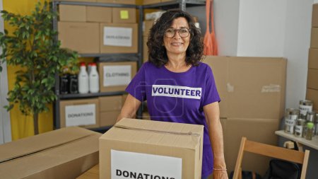 Téléchargez les photos : Moyen Age hispanique femme bénévole souriant confiance debout au centre de charité - en image libre de droit