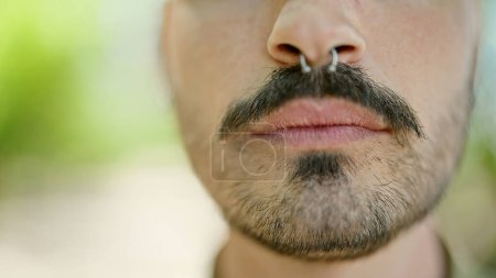Téléchargez les photos : Jeune homme hispanique debout avec un visage sérieux au parc - en image libre de droit