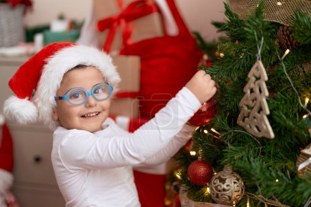 Téléchargez les photos : Adorable bambin hispanique décorant l'arbre de Noël à la maison - en image libre de droit