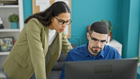 Téléchargez les photos : Duo dynamique au travail, deux travailleurs professionnels, homme et femme, évoquant le succès à leur bureau à l'intérieur du bureau, exploitant la technologie avec l'ordinateur - en image libre de droit