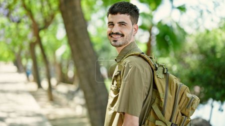 Téléchargez les photos : Jeune homme hispanique touriste portant un sac à dos souriant au parc - en image libre de droit