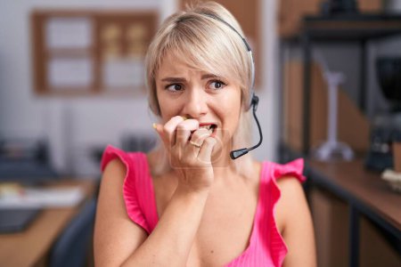 Photo for Young caucasian woman wearing call center agent headset looking stressed and nervous with hands on mouth biting nails. anxiety problem. - Royalty Free Image