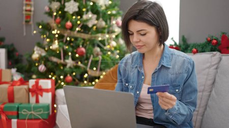 Foto de Mujer caucásica joven haciendo compras en línea de Navidad con el ordenador portátil en casa - Imagen libre de derechos