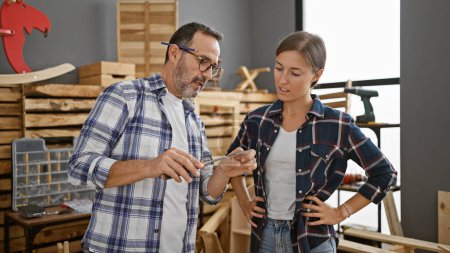 Photo for Two mates in the carpentry biz, a man and a woman, chinwagging while the timber whispers. screwdriver in hand, they sculpt their profession, shaping woodwork into furniture with serious dedication. - Royalty Free Image