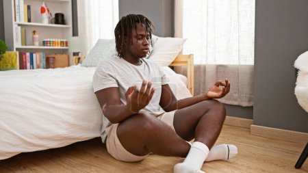 Téléchargez les photos : Afro-américain faire de l'exercice de yoga assis sur le sol de la chambre - en image libre de droit