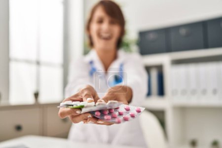 Téléchargez les photos : Jeune femme médecin tenant des pilules souriant et riant fort à haute voix parce que drôle blague folle. - en image libre de droit