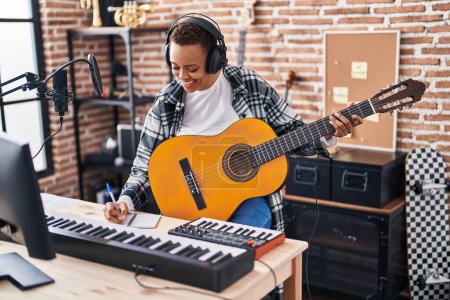 Téléchargez les photos : African american woman musician composing song playing classical guitar at music studio - en image libre de droit